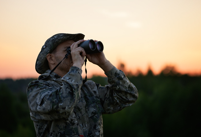 A guided birdwatching scanning treetops with binoculars